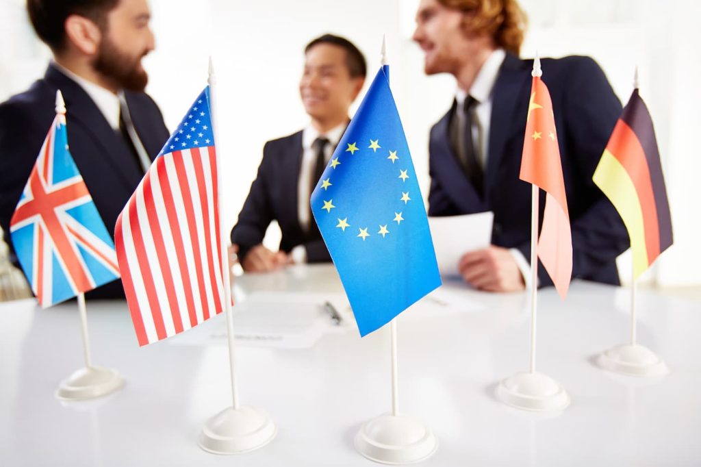 Como tirar visto americano A1. Pessoas sentadas e na mesa bandeiras dos respectivos paises