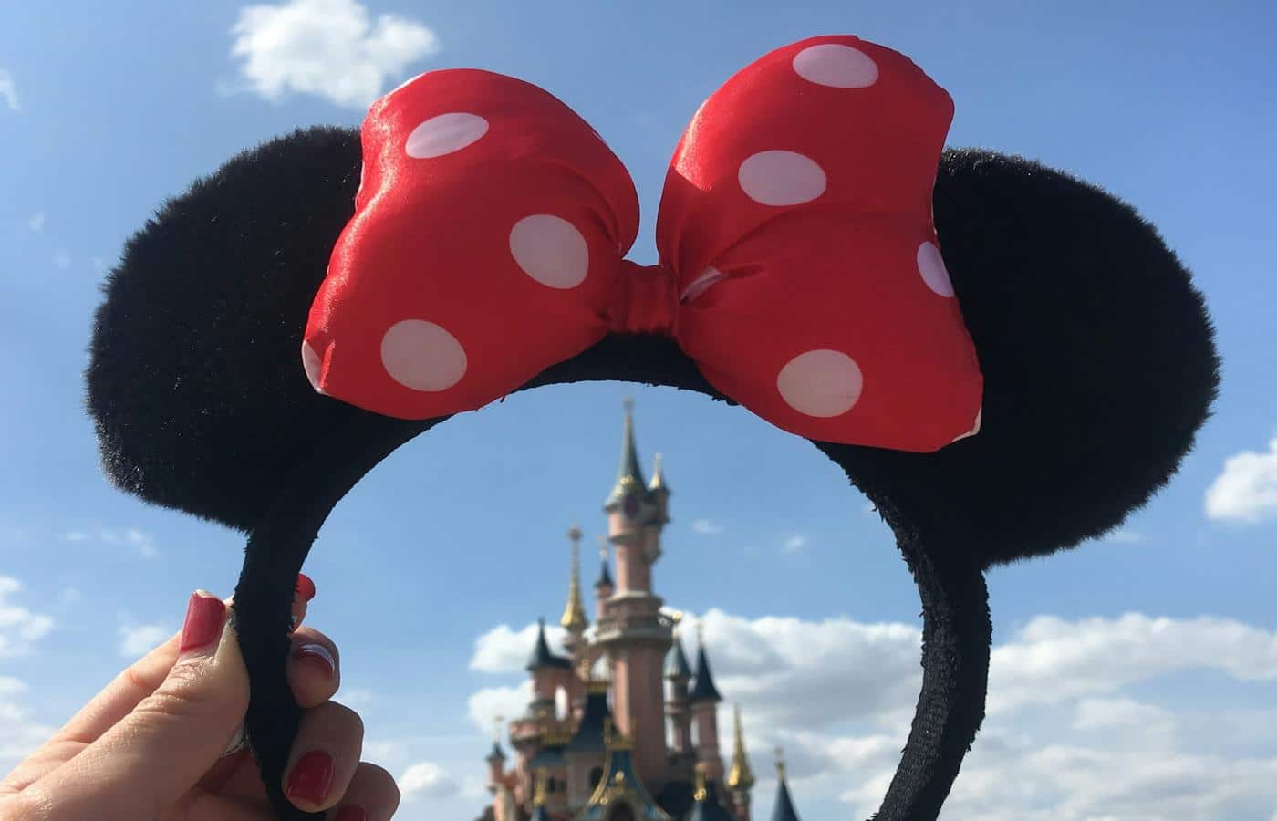 Pessoa segurando tiara da Minnie em volta do castelo do Parque temático da Disney, nos EUA
