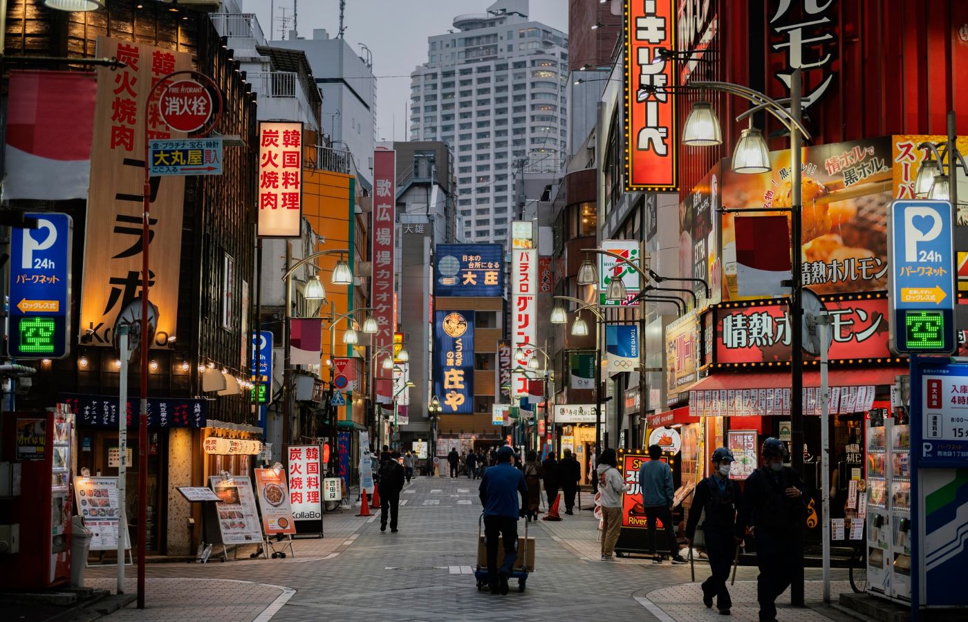 Rua lotada no Japão com muitos estabelecimentos e prédios à distância