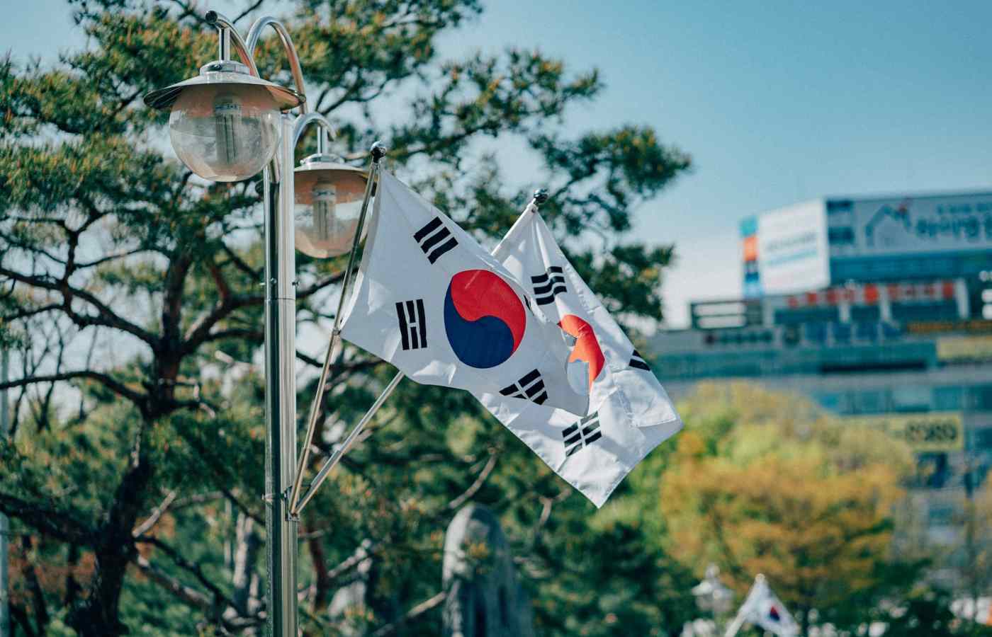 Rua em Bucheon, na Coreia do Sul, com duas bandeiras do país penduradas e muitas árvores