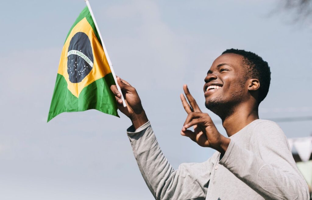 Estrangeiro com RNE segurando bandeira do Brasil