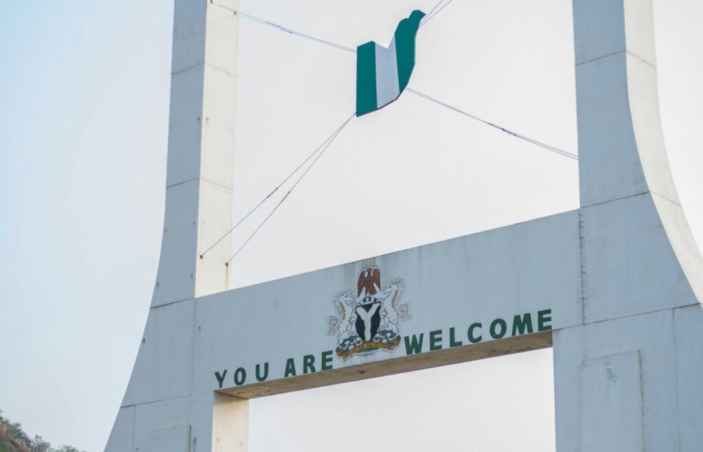 Portão com bandeira da Nigéria dando boas-vindas a quem está chegando.